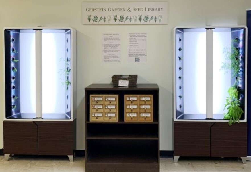 Shelf with drawers of seed packets, between two vertical gardening units growing plants